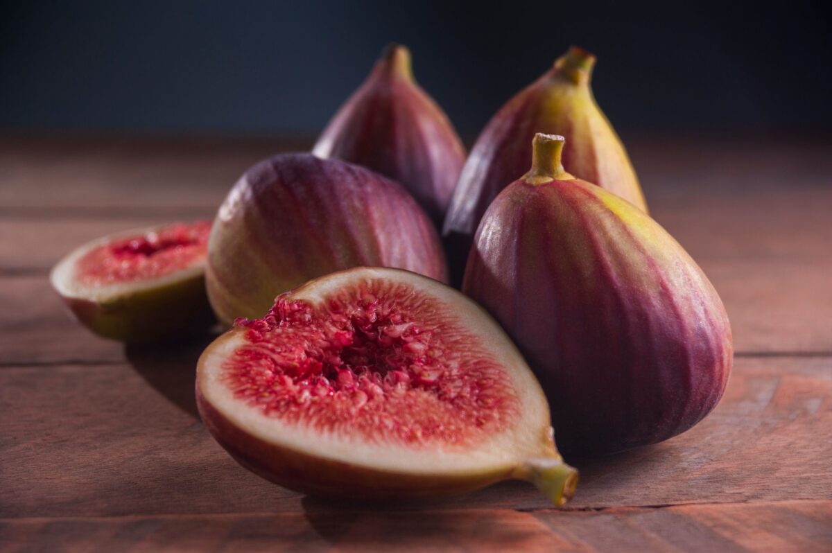 Figues fraîches violettes entières et coupées en deux sur une planche en bois